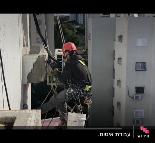 אדם עם קסדה אדומה עובד על איטום קיר חיצוני